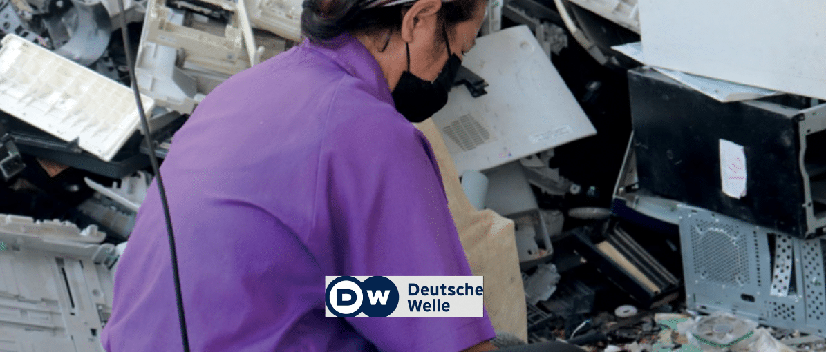 a woman recycling worker sitting in a pile of plastic e-waste, DW logo in foreground