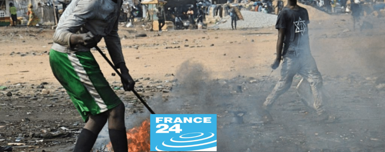 men burning a small pile of plastic trash, France24 logo in foreground
