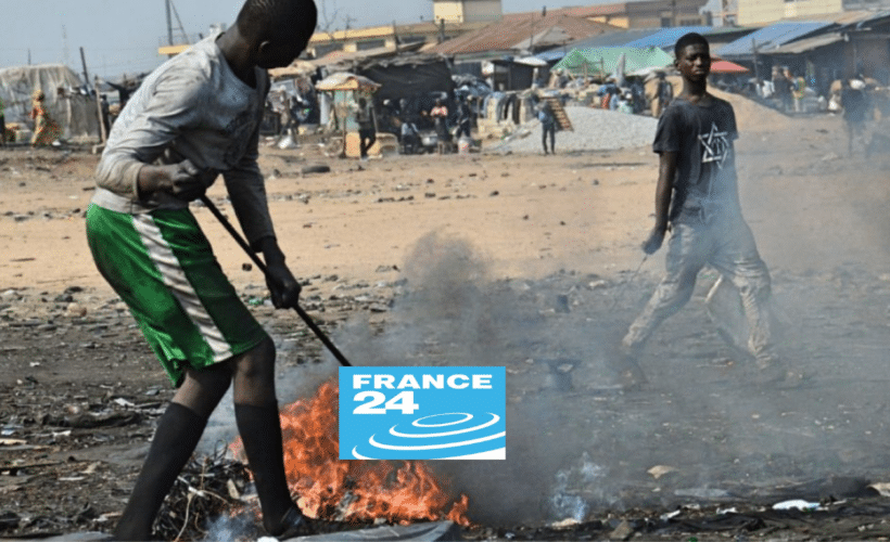 men burning a small pile of plastic trash, France24 logo in foreground