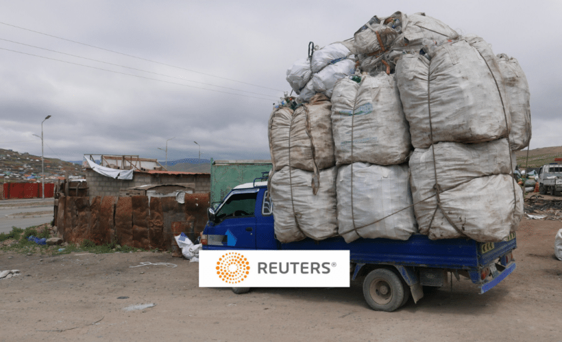 a truck piled high with trash, Reuters logo in foreground