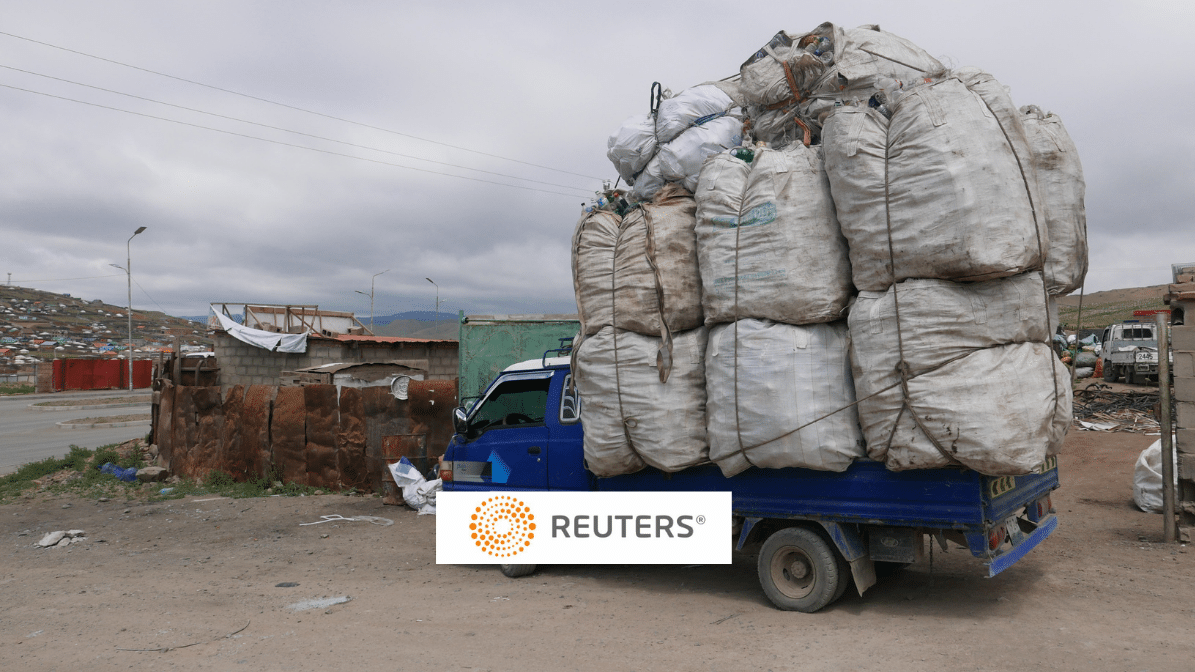 a truck piled high with trash, Reuters logo in foreground