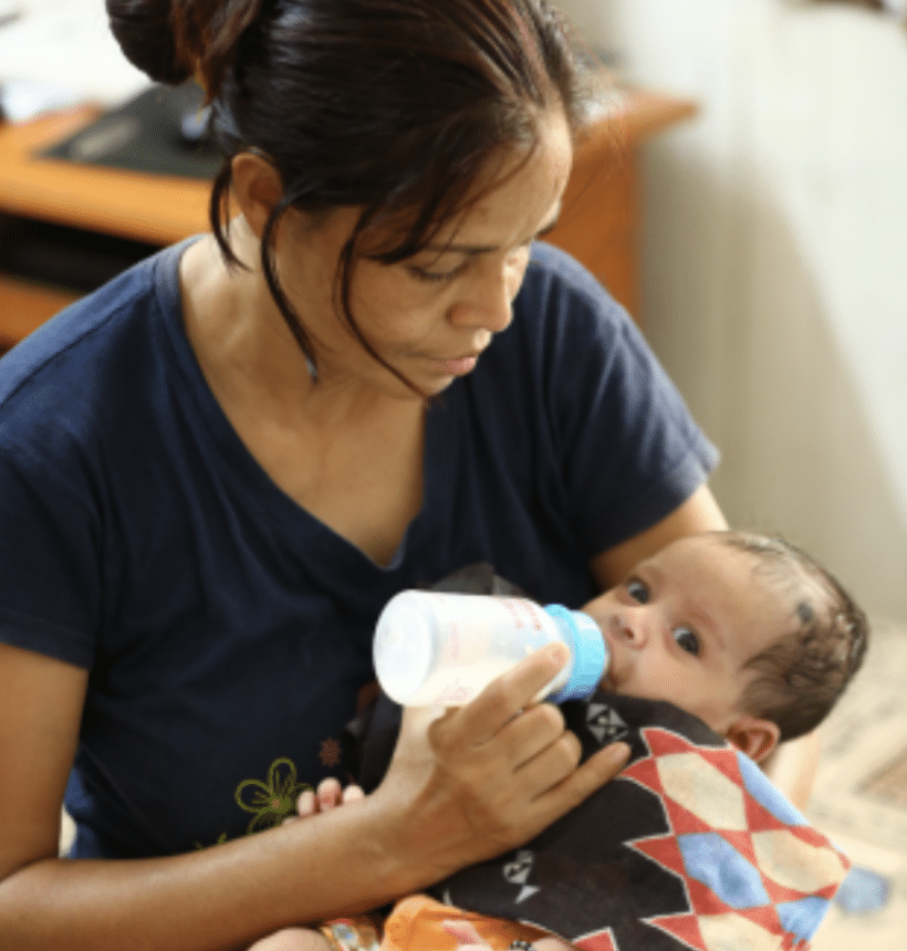 a woman bottle-feeding a baby